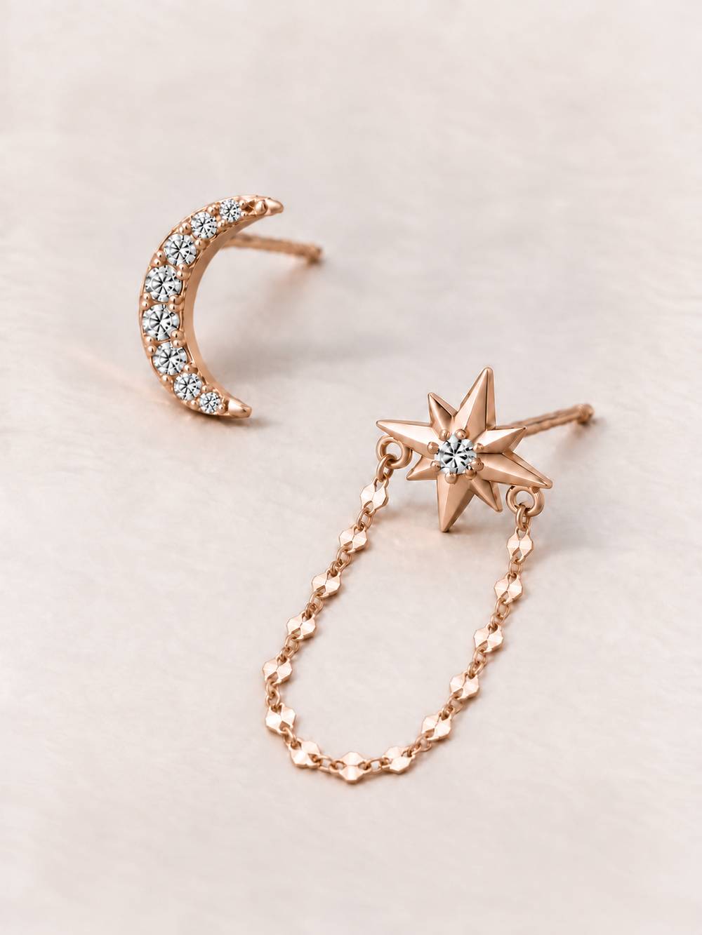 Crescent Moon and Star Chain Earrings shown angled on a warm neutral background