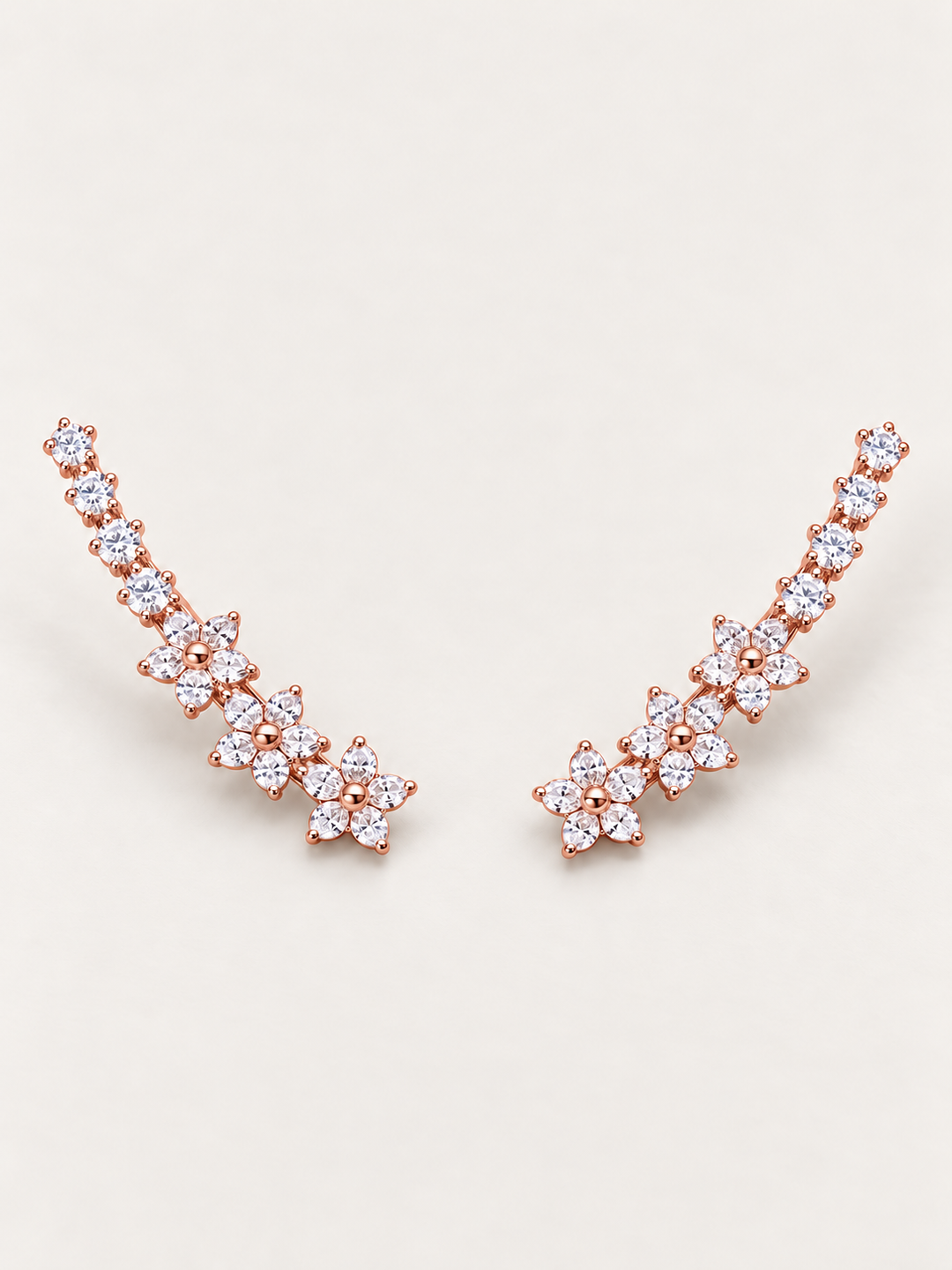 Rose gold Crystal Flower Ear Crawler Earrings on a warm neutral background