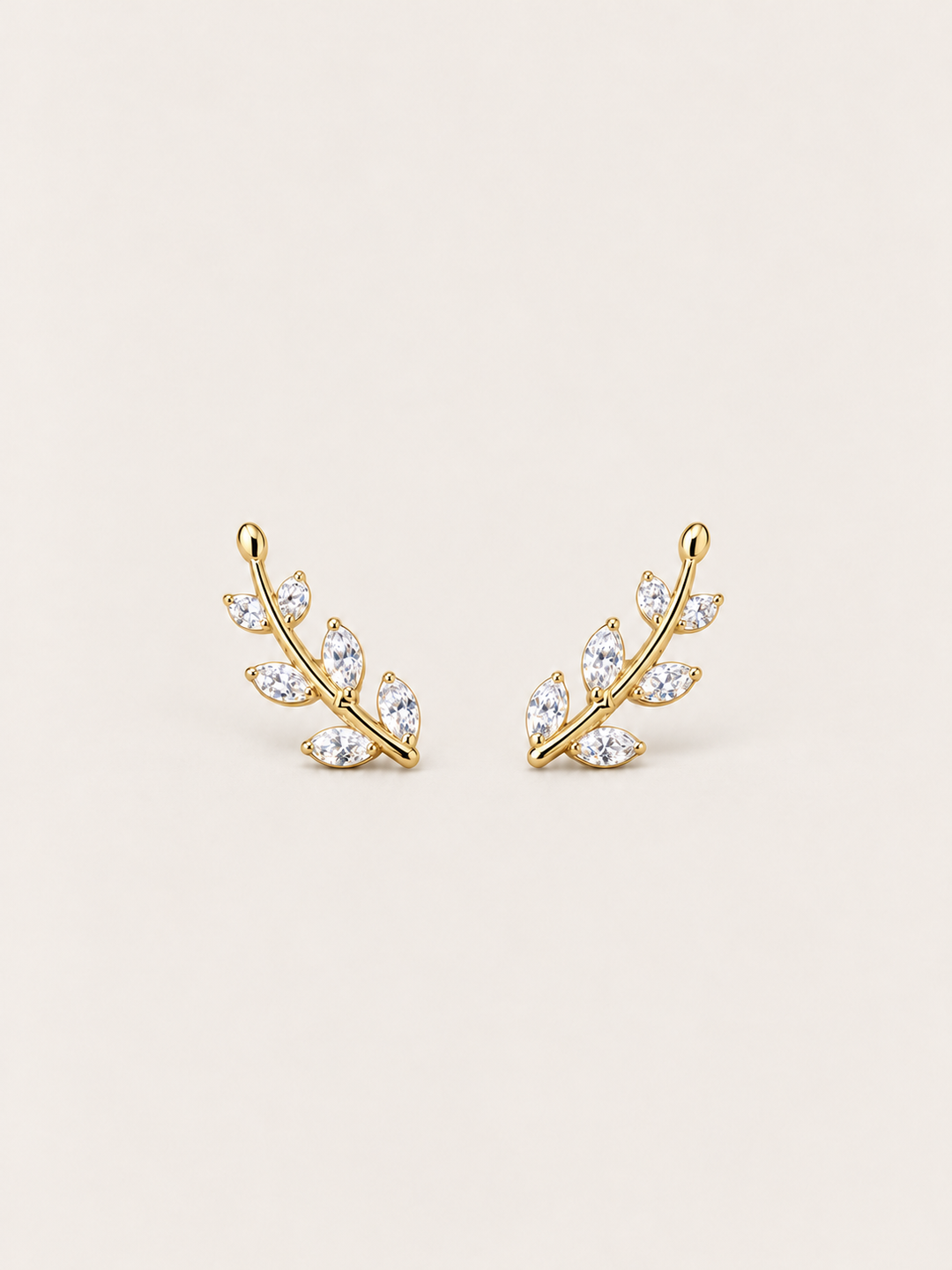 Crystal Leaf Ear Crawler Earrings in gold shown on a warm neutral background