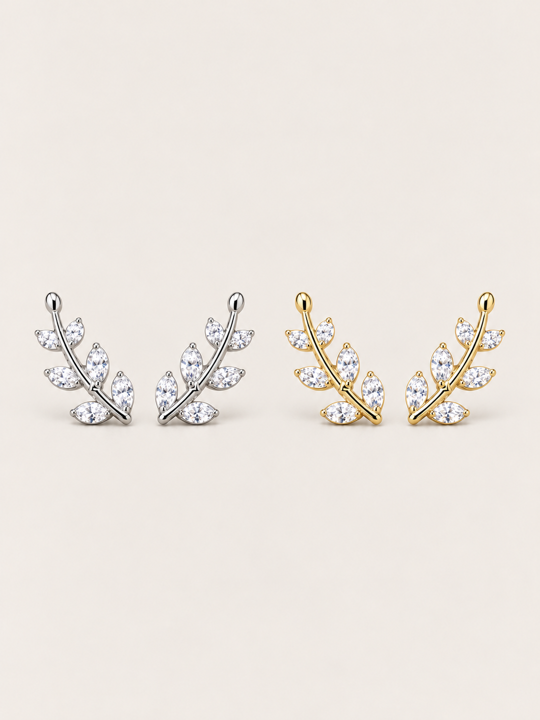 Crystal Leaf Ear Crawler Earrings in silver and gold shown on a warm neutral background