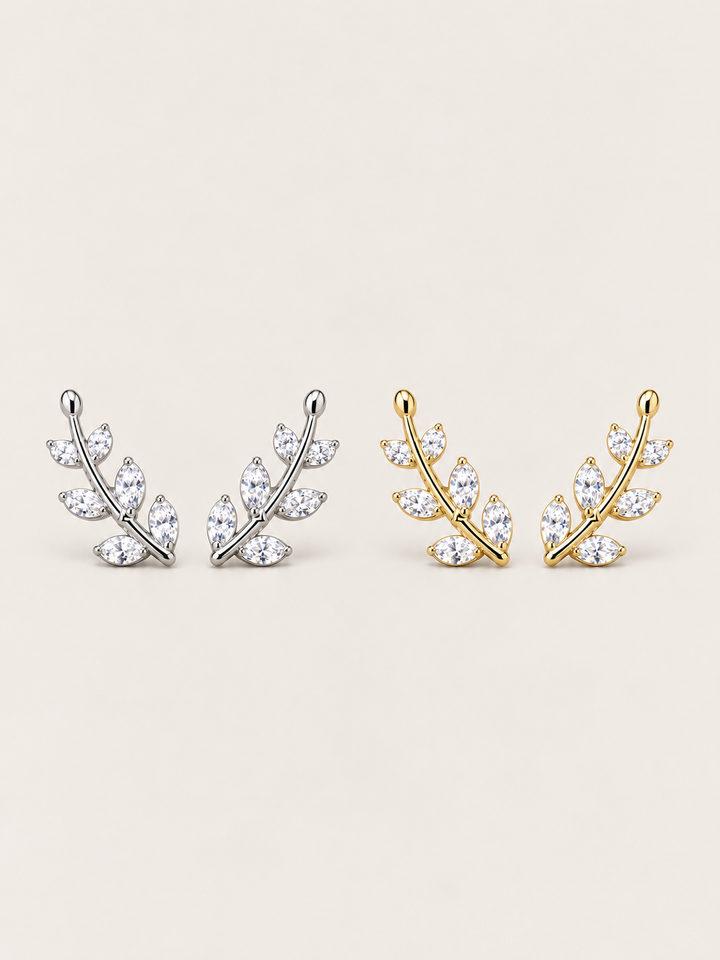Crystal Leaf Ear Crawler Earrings in silver and gold shown on a warm neutral background
