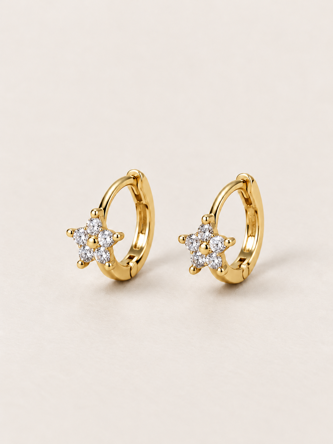 Gold Crystal Star Huggie Earrings shown on a warm neutral background