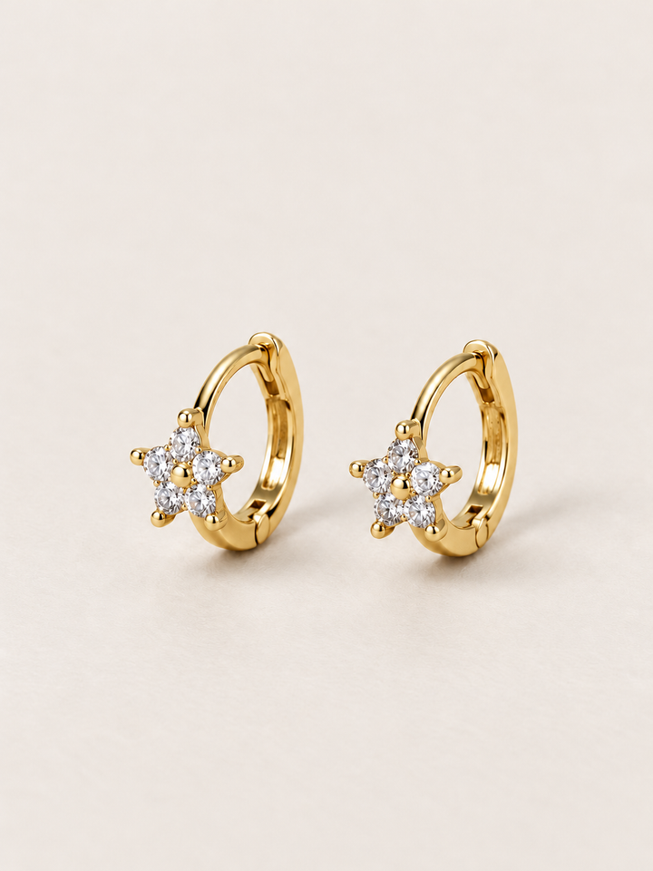 Gold Crystal Star Huggie Earrings shown on a warm neutral background