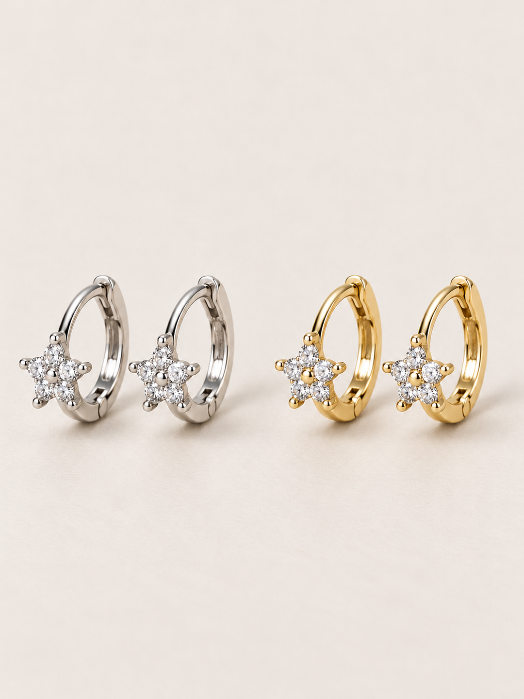 Crystal Star Huggie Earrings in silver and gold shown on a warm neutral background