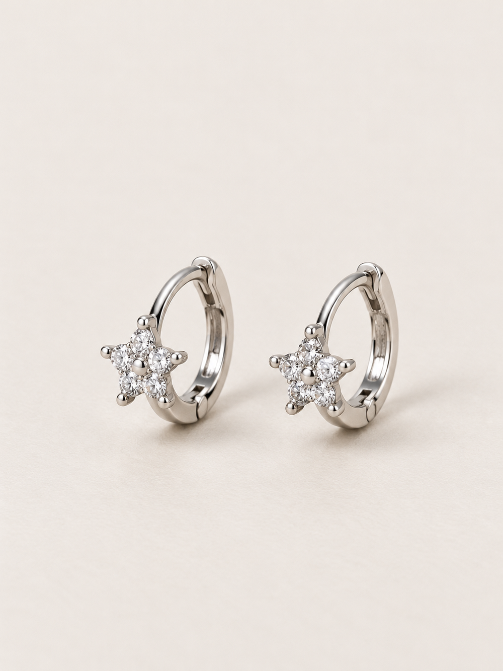 Silver Crystal Star Huggie Earrings shown on a warm neutral background