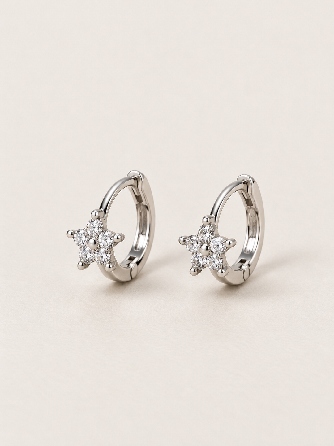 Silver Crystal Star Huggie Earrings shown on a warm neutral background