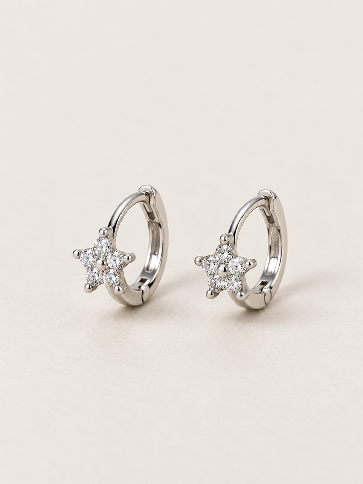 Silver Crystal Star Huggie Earrings shown on a warm neutral background
