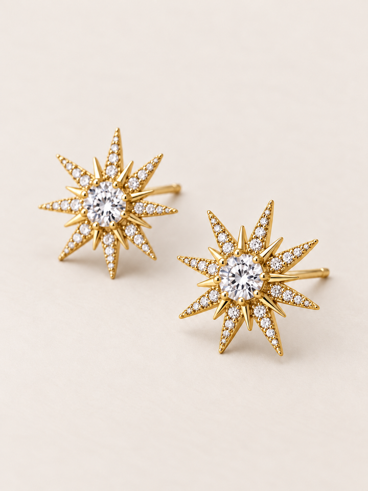 Crystal Starburst Stud Earrings in Gold shown angled on a warm neutral background
