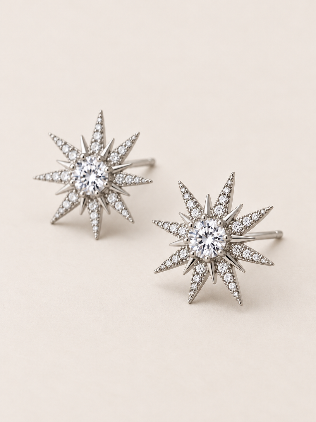 Crystal Starburst Stud Earrings in Silver shown angled on a warm neutral background