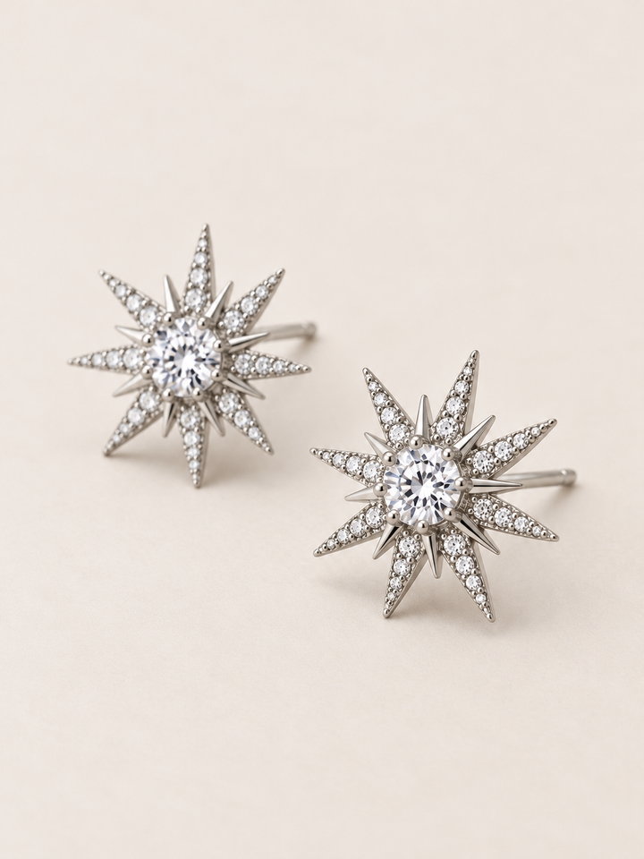 Crystal Starburst Stud Earrings in Silver shown angled on a warm neutral background