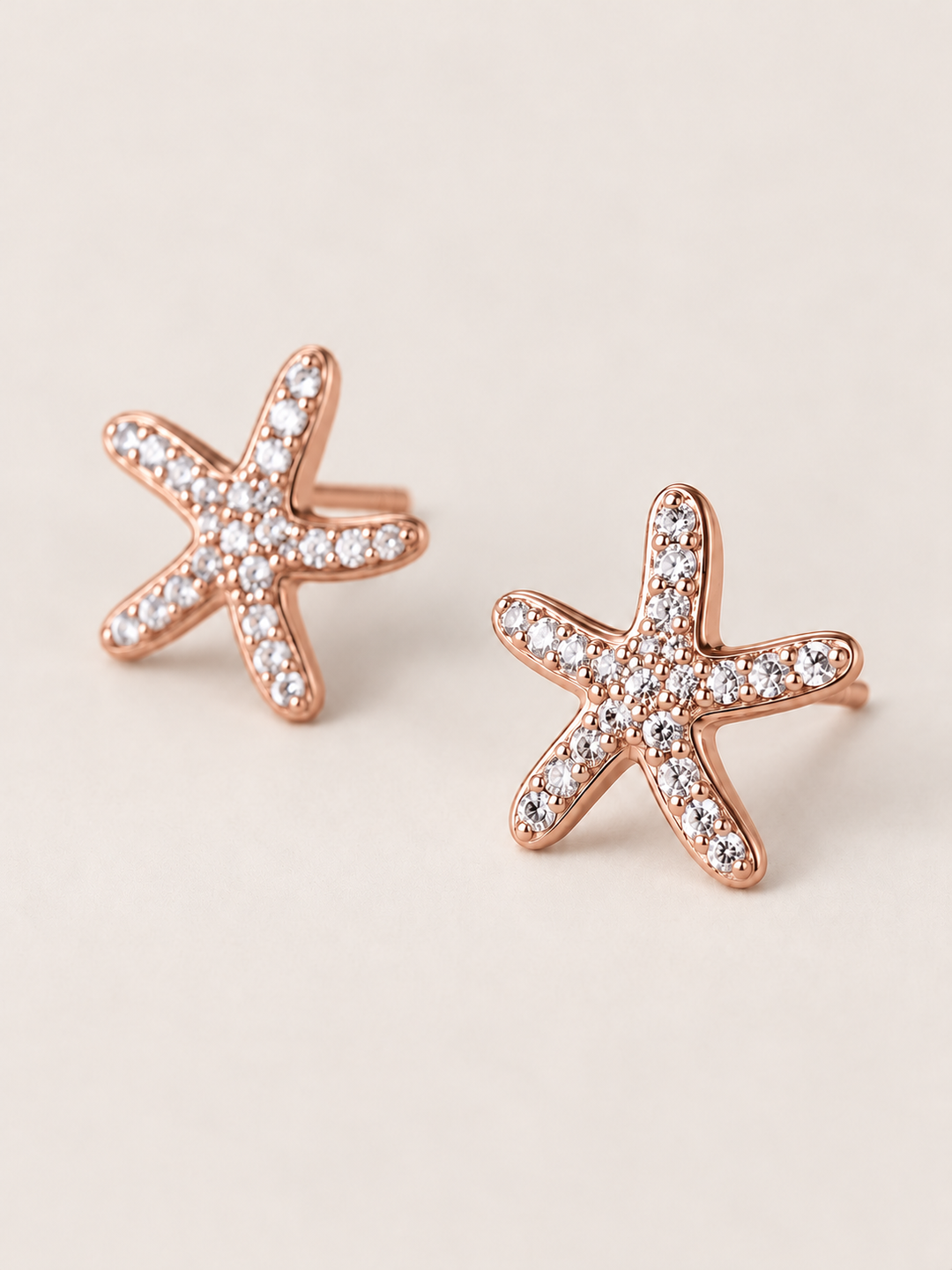 Rose Gold Crystal Starfish Stud Earrings shown angled on a warm neutral background