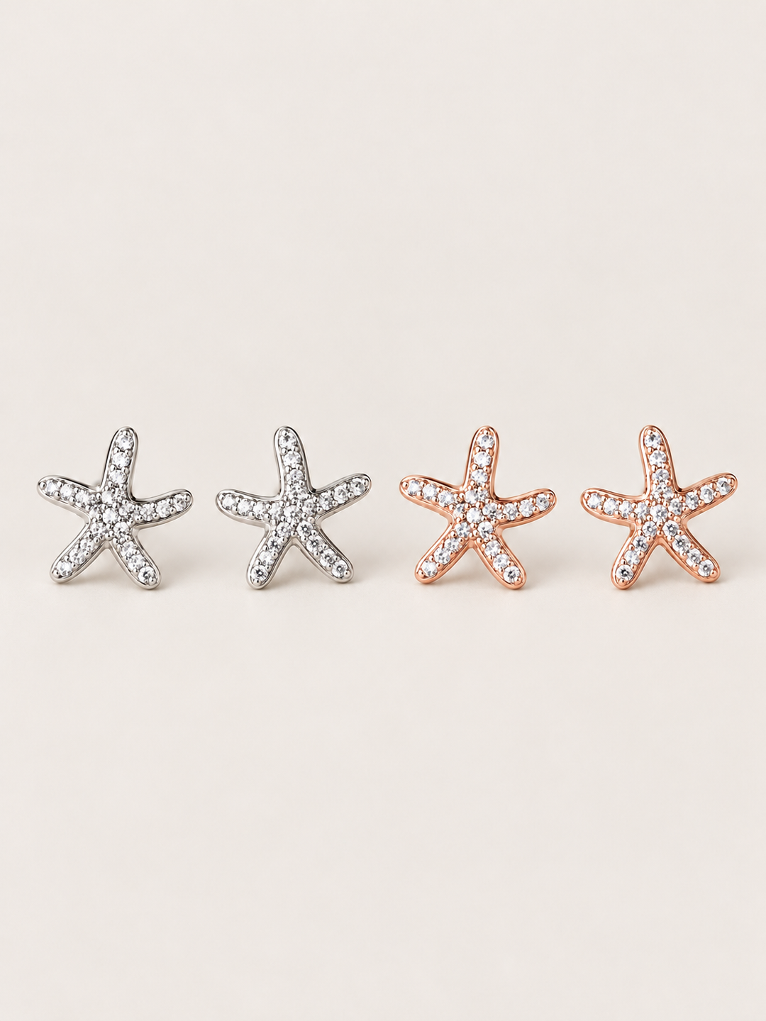 Crystal Starfish Stud Earrings in Silver and Rose Gold shown on a warm neutral background