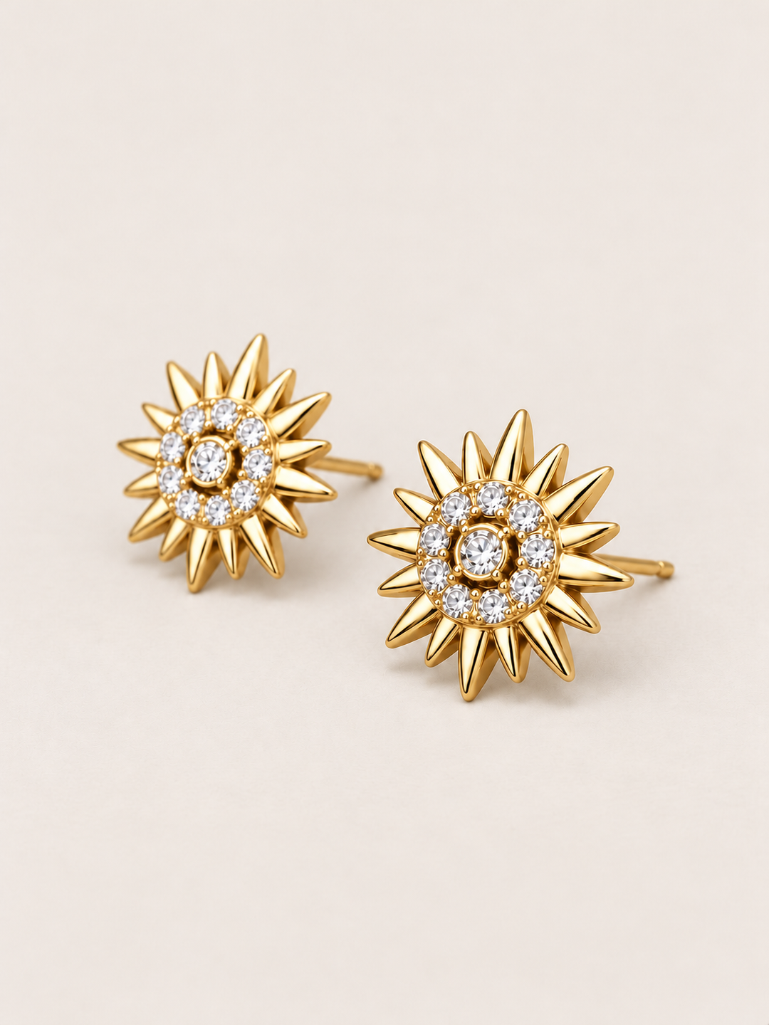 Crystal Sunburst Stud Earrings in Gold shown angled on a warm neutral background