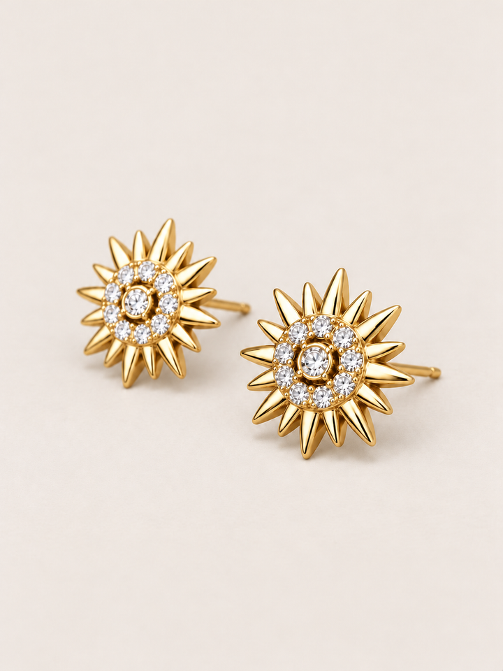 Crystal Sunburst Stud Earrings in Gold shown angled on a warm neutral background