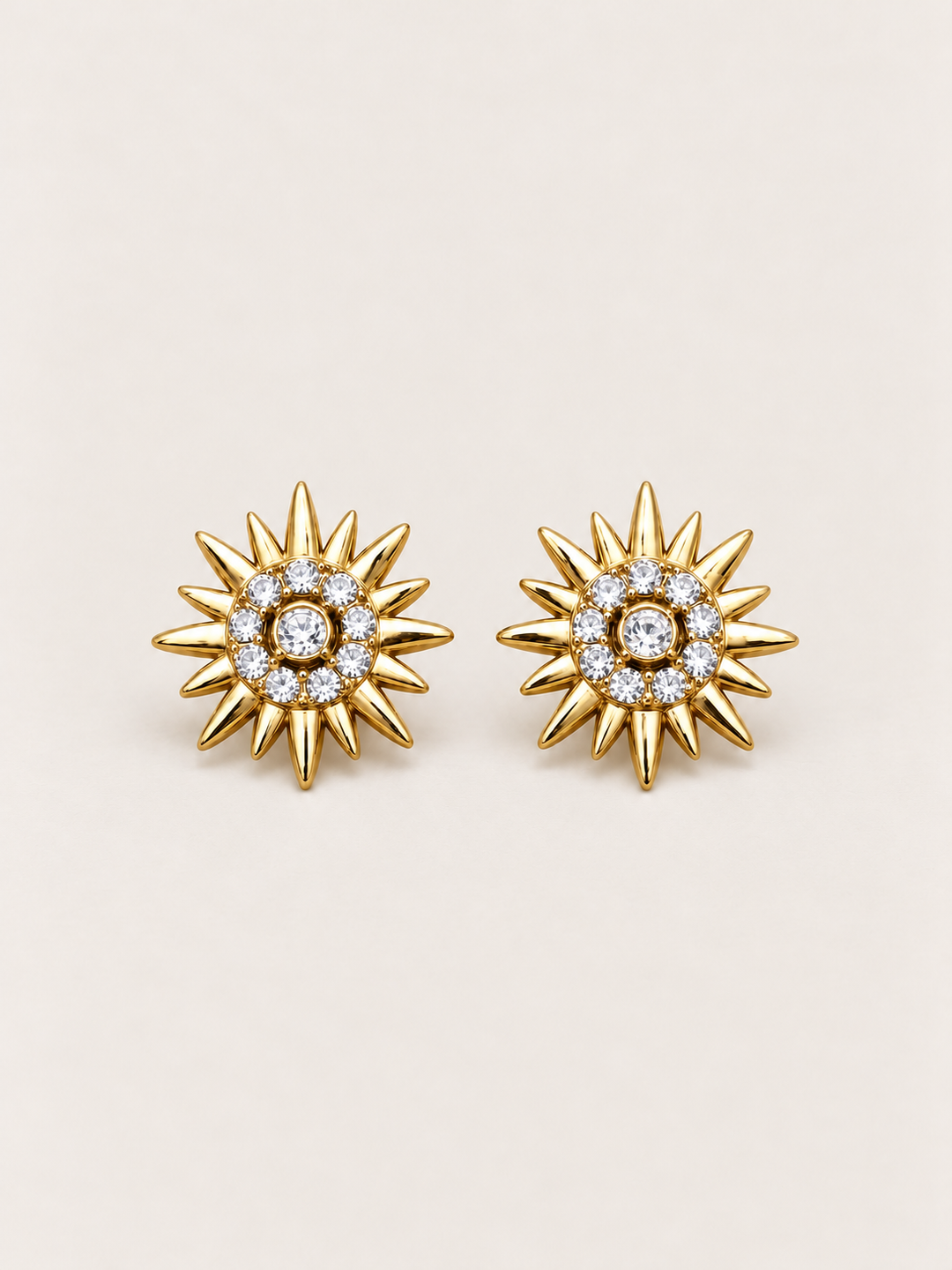 Crystal Sunburst Stud Earrings in Gold shown on a warm neutral background