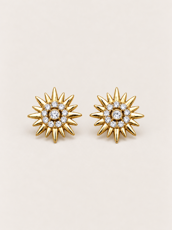 Crystal Sunburst Stud Earrings in Gold shown on a warm neutral background