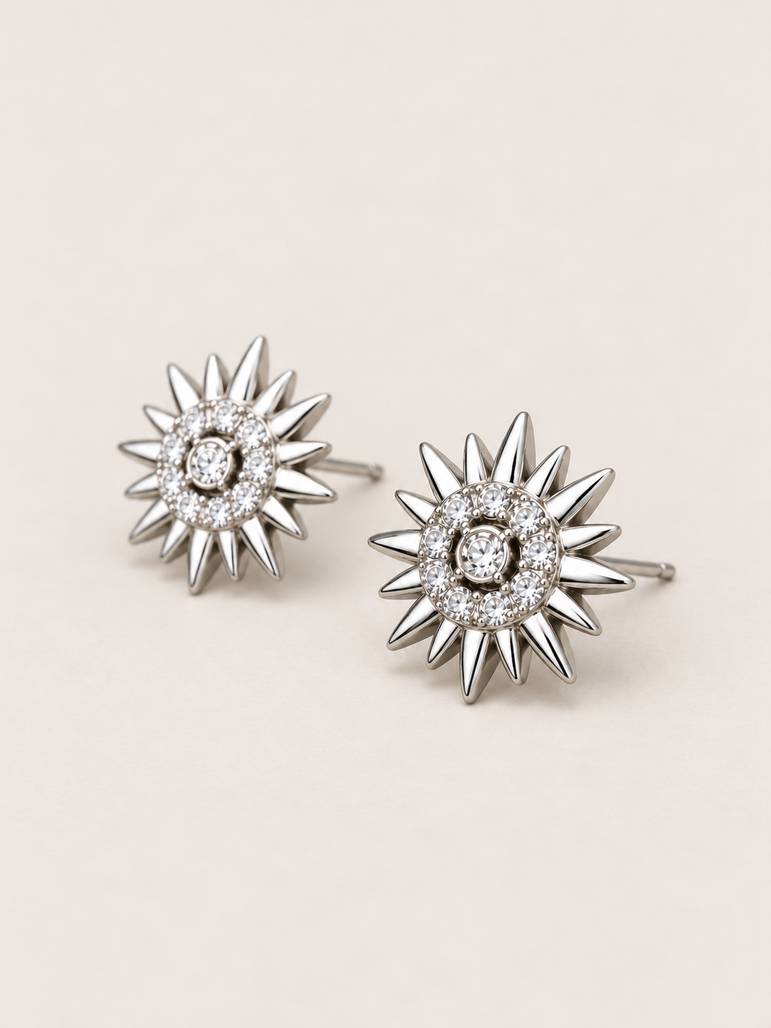 Crystal Sunburst Stud Earrings in Silver shown angled on a warm neutral background