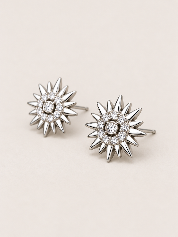 Crystal Sunburst Stud Earrings in Silver shown angled on a warm neutral background