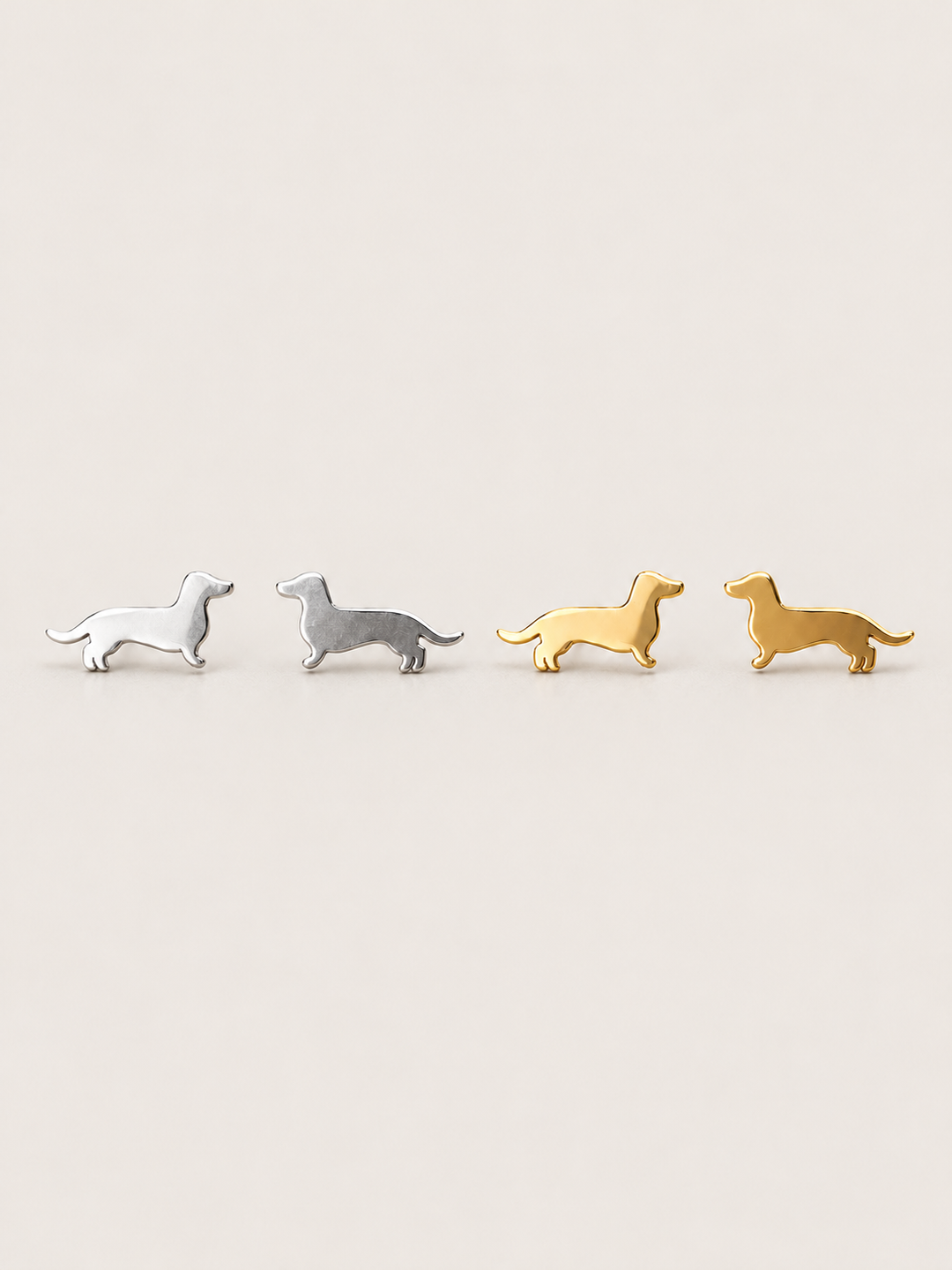 Dachshund Stud Earrings in silver and gold shown on a warm neutral background