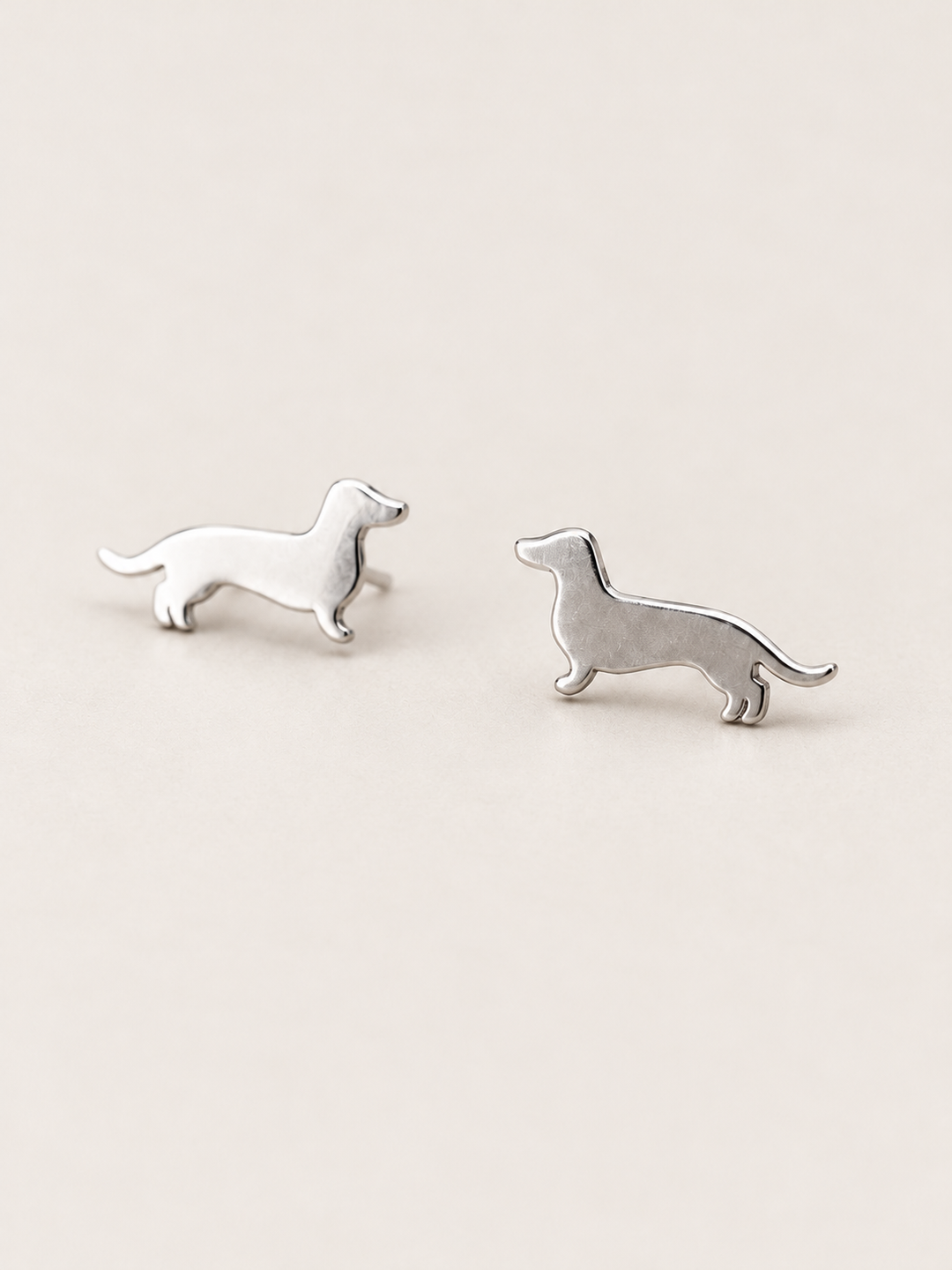 Dachshund Stud Earrings in silver shown angled on a warm neutral background