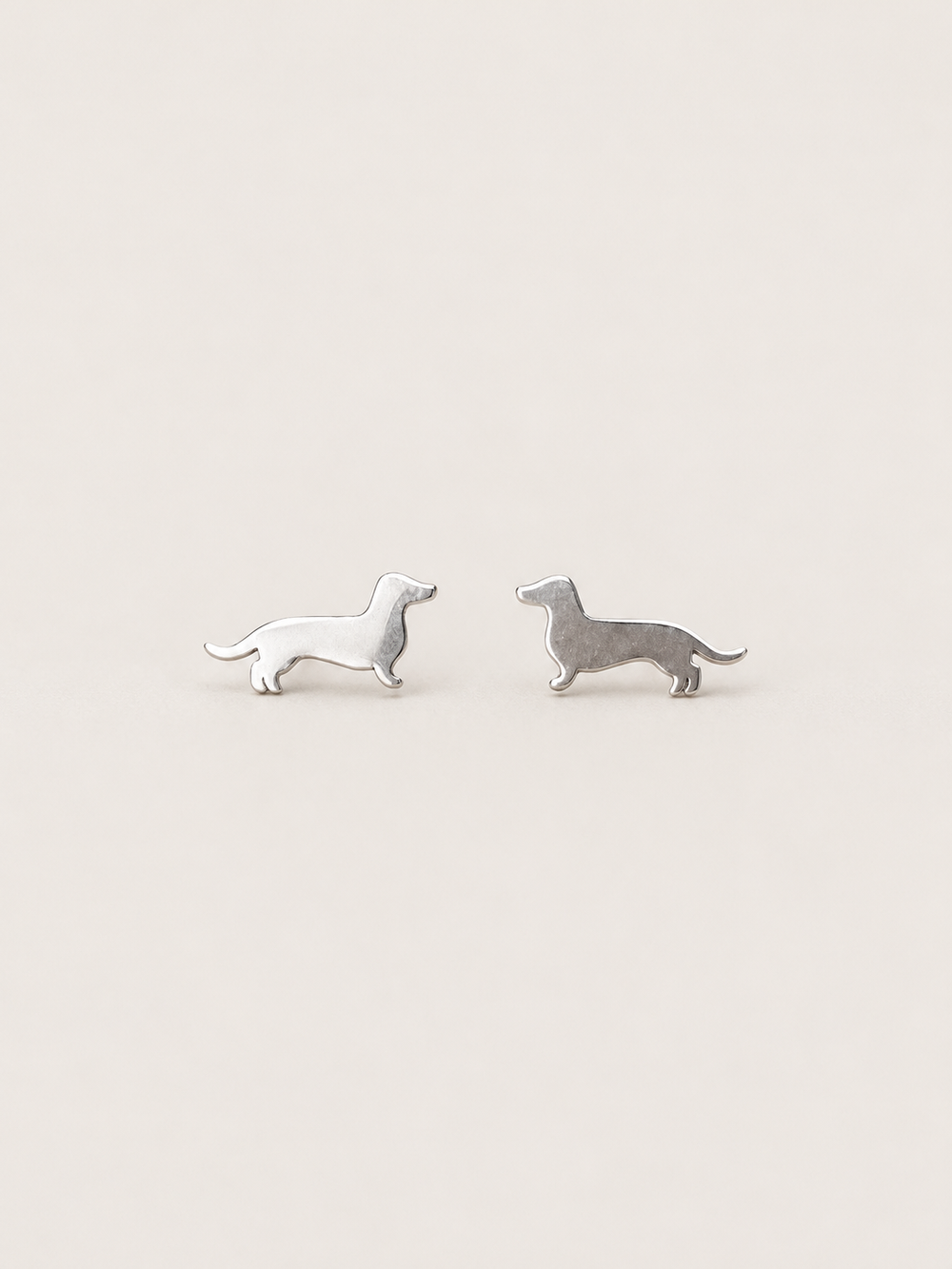 Dachshund Stud Earrings in silver shown on a warm neutral background