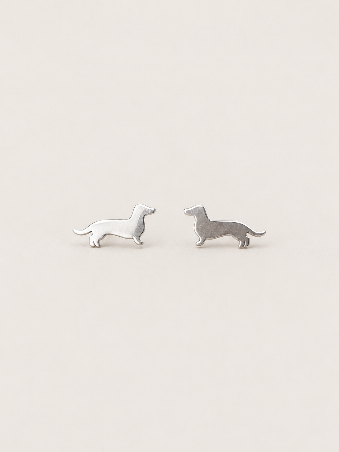 Dachshund Stud Earrings in silver shown on a warm neutral background