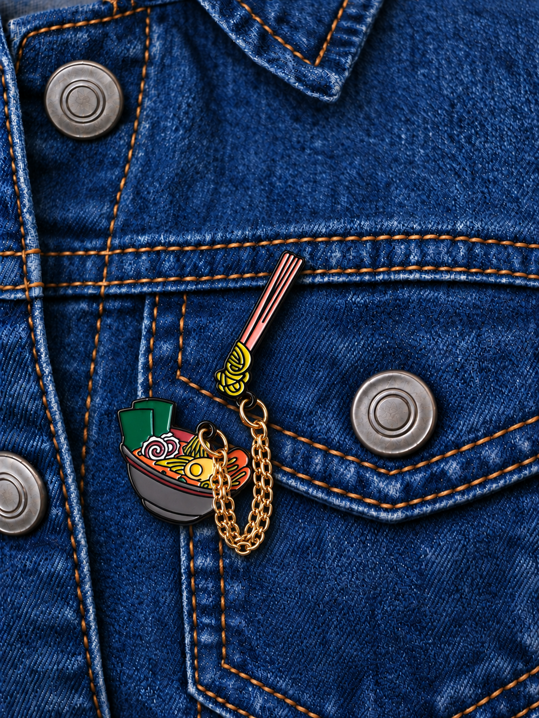 Dangling Ramen Bowl Pin displayed on a dark indigo denim jacket beside a metal button