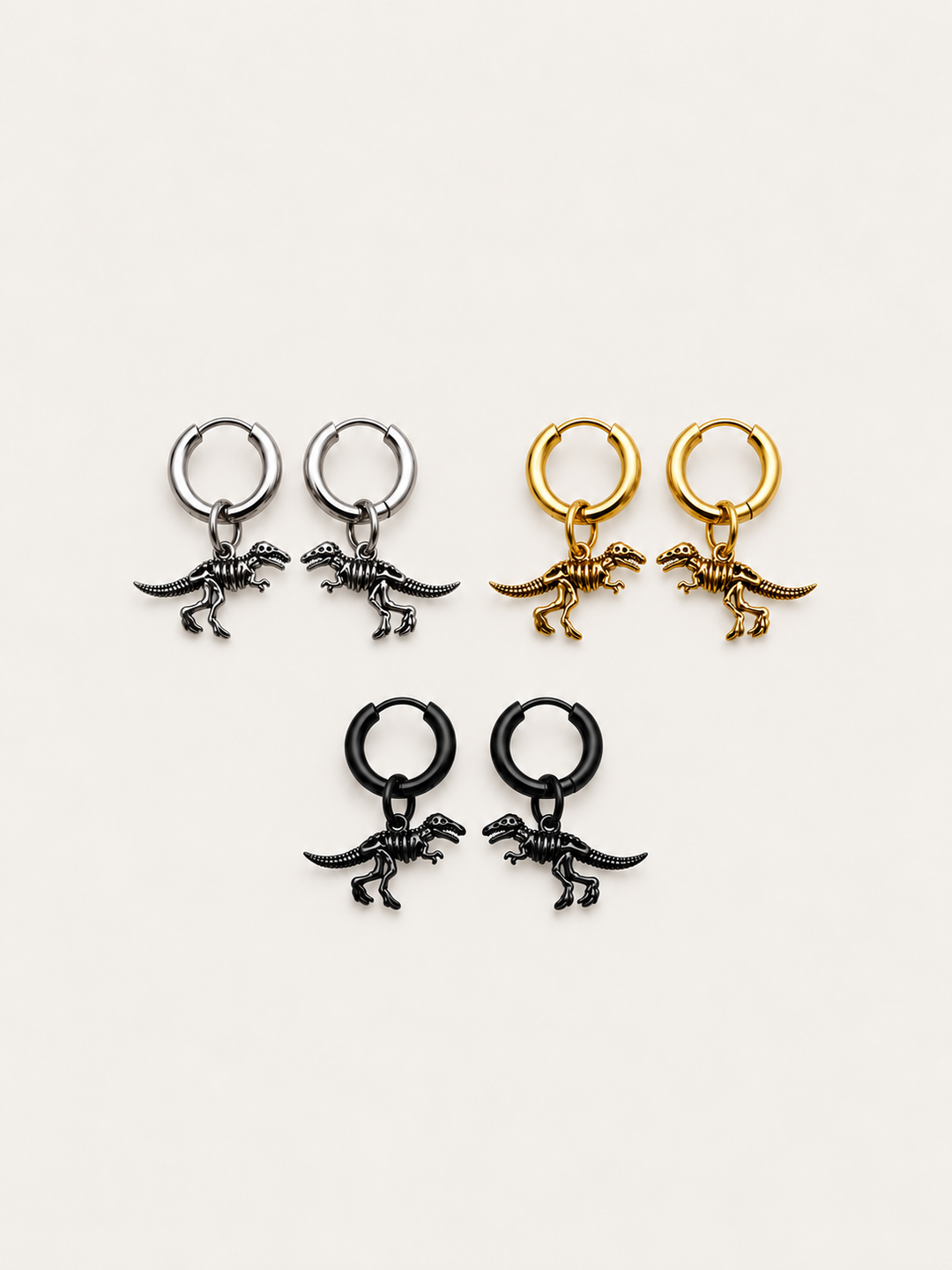 Dinosaur Skeleton Hoop Earrings in silver, gold, and black shown on a warm neutral background