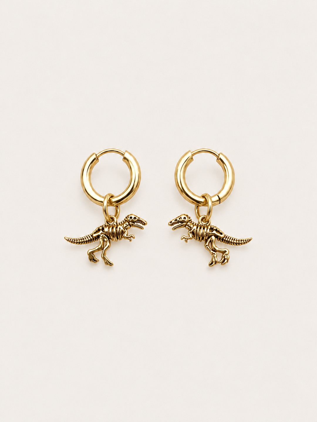Dinosaur Skeleton Hoop Earrings — gold main on a warm neutral background