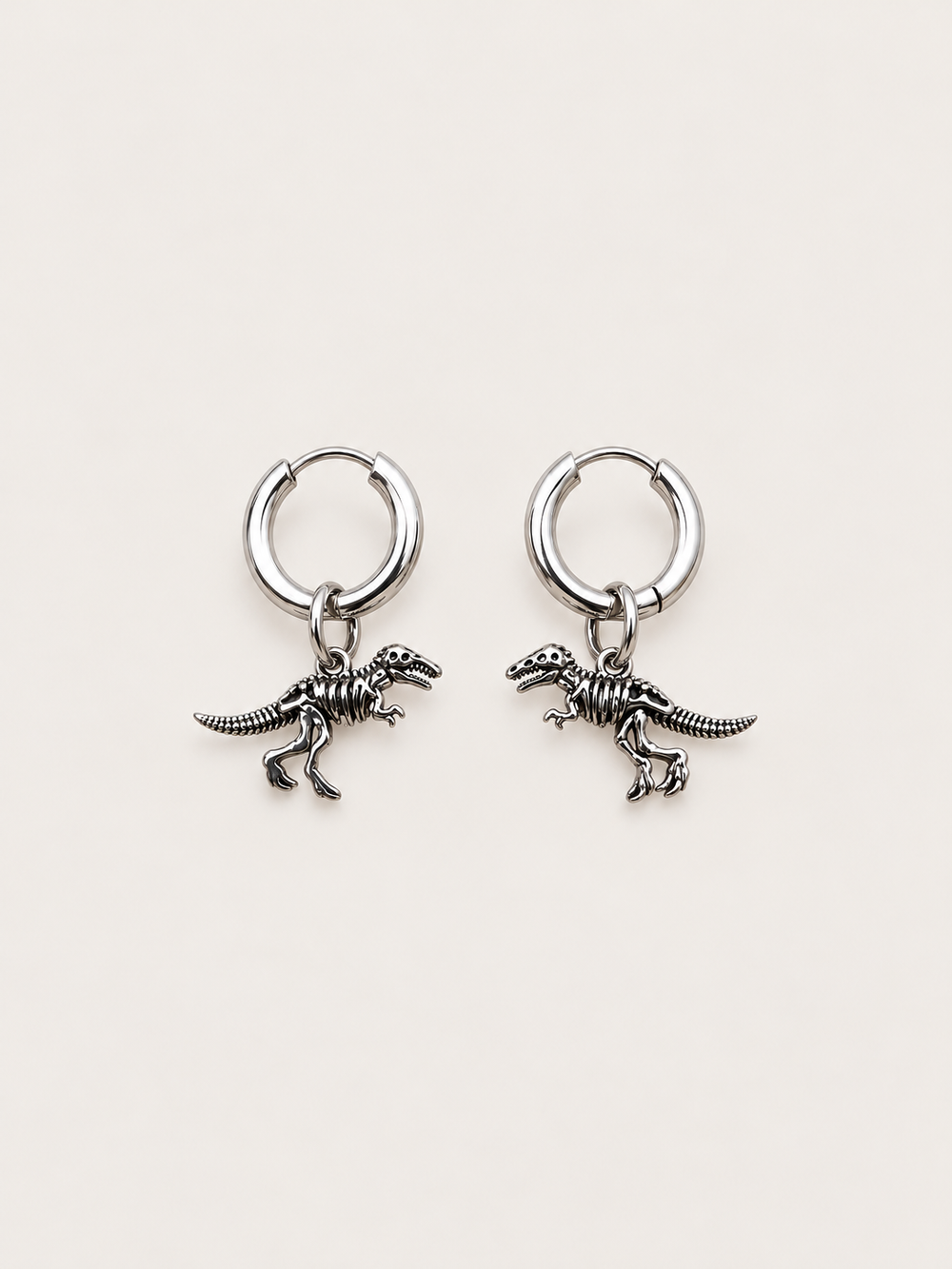 Dinosaur Skeleton Hoop Earrings — silver main on a warm neutral background