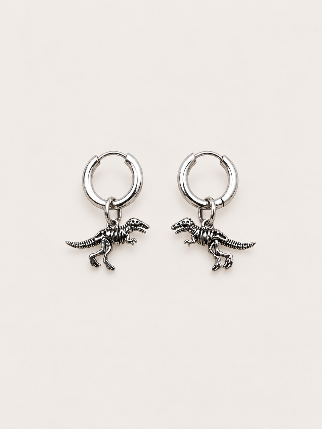 Dinosaur Skeleton Hoop Earrings — silver main on a warm neutral background