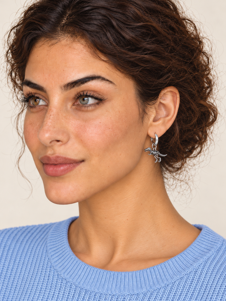 Dinosaur Skeleton Hoop Earrings — silver model on a warm neutral background