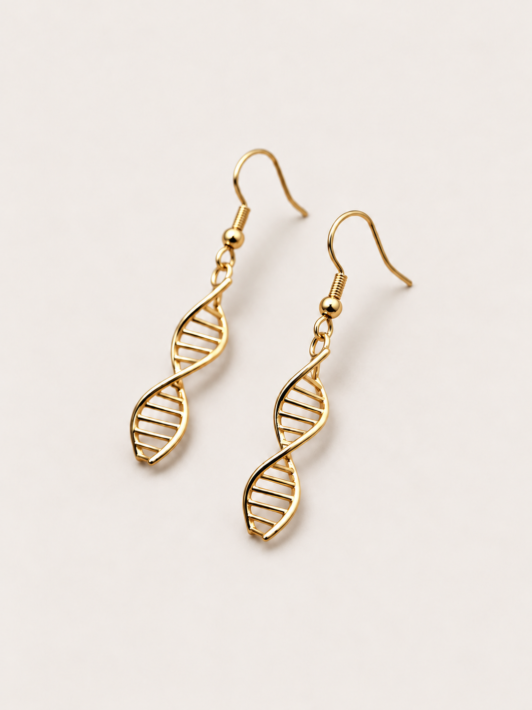 Gold DNA Double Helix Earrings shown angled on a warm neutral background
