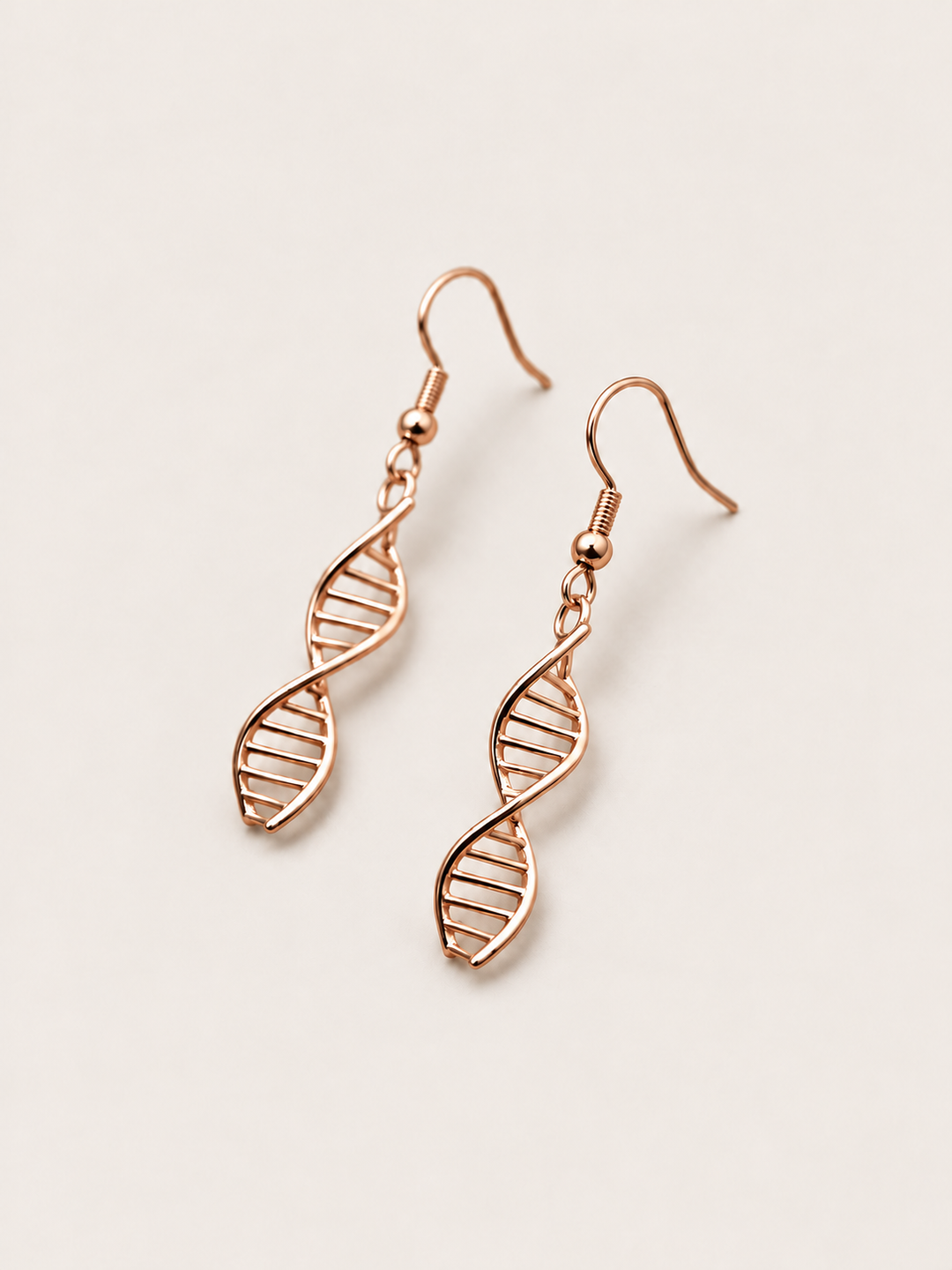 Rose Gold DNA Double Helix Earrings shown angled on a warm neutral background