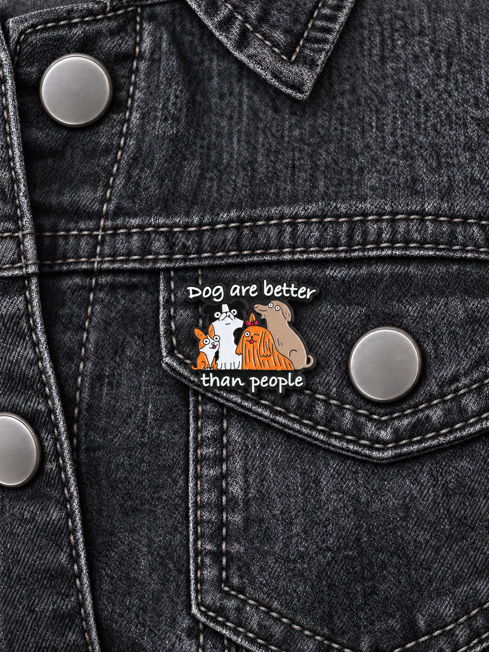 Dogs Are Better Than People Pin displayed on a charcoal denim jacket beside a metal button