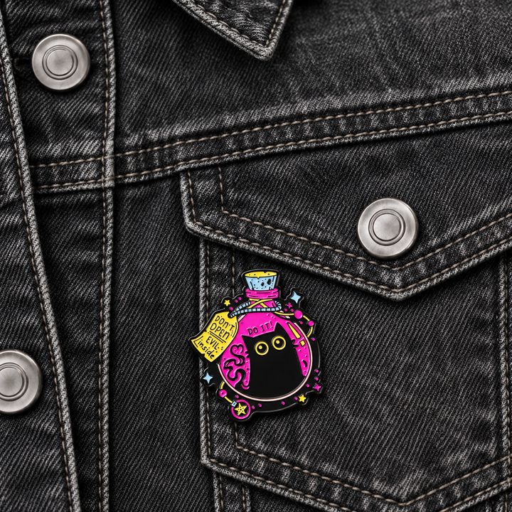 Don't Open Evil Inside Cat Potion Pin displayed on a blue denim jacket beside a metal button