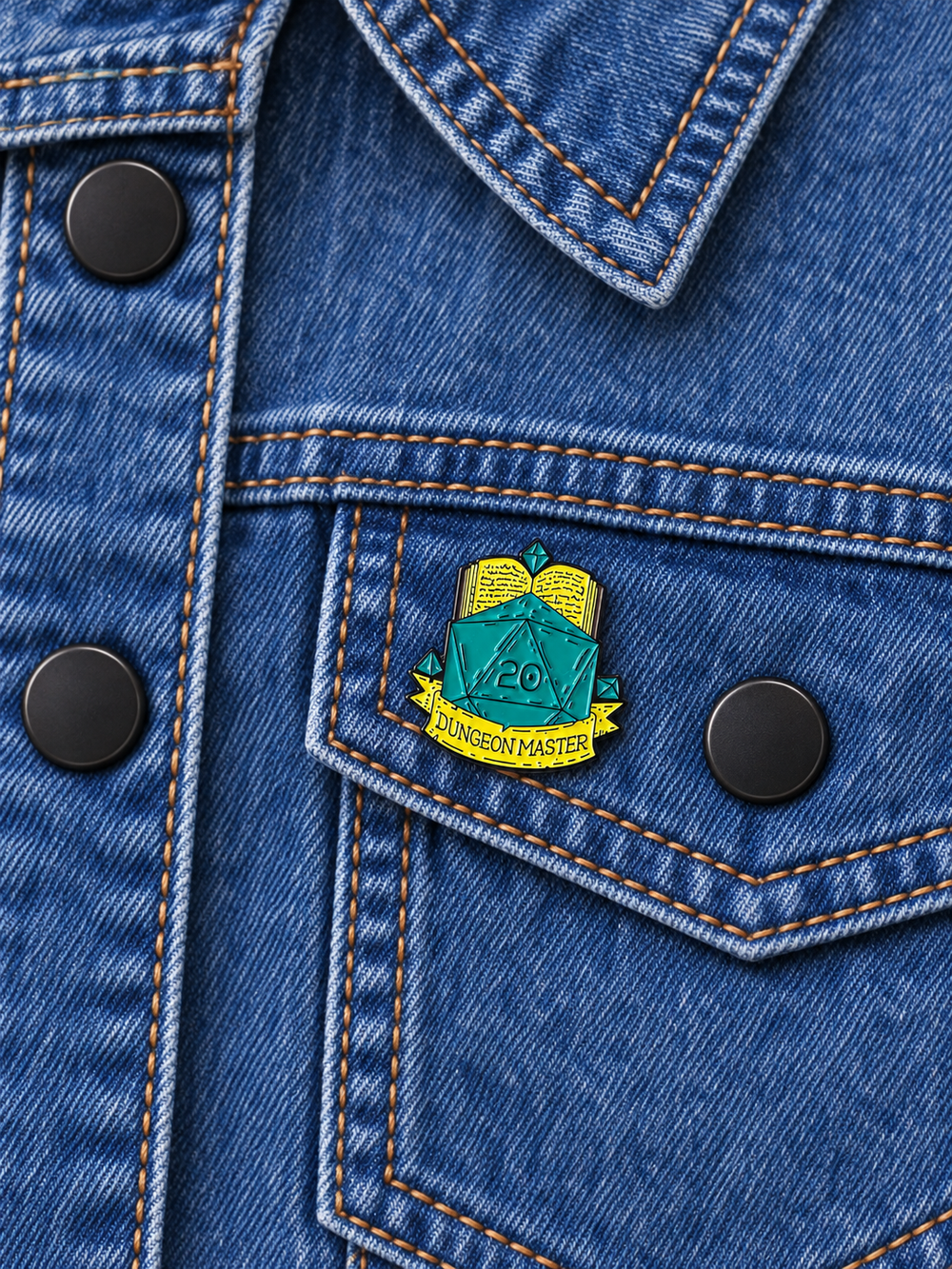 Dungeon Master D20 Pin displayed on a medium-blue denim jacket beside a metal button