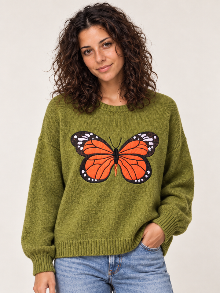 Front view of model wearing green embroidered monarch butterfly sweater