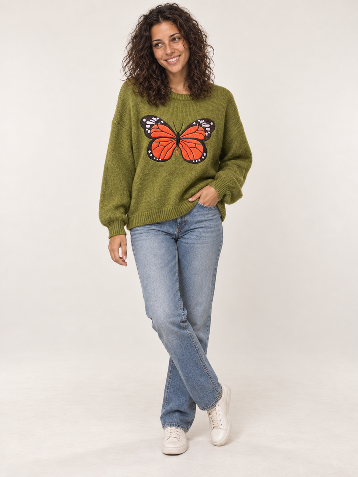 Full body view of model wearing green embroidered monarch butterfly sweater