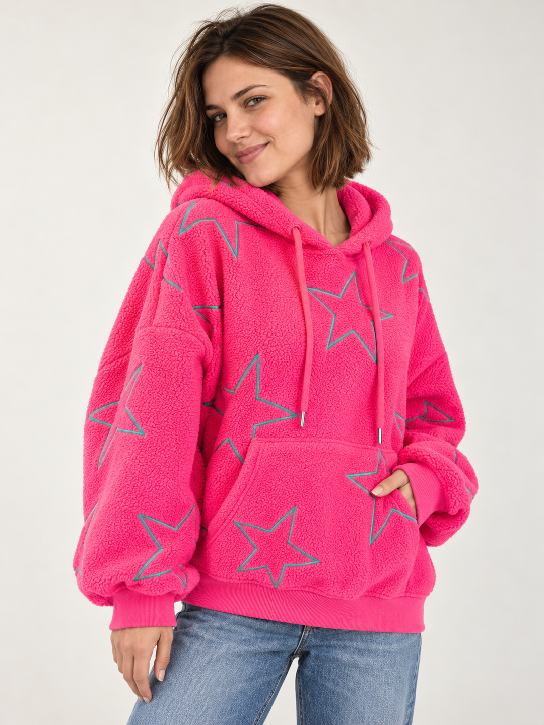 Model wearing embroidered star sherpa hoodie in pink, angled view