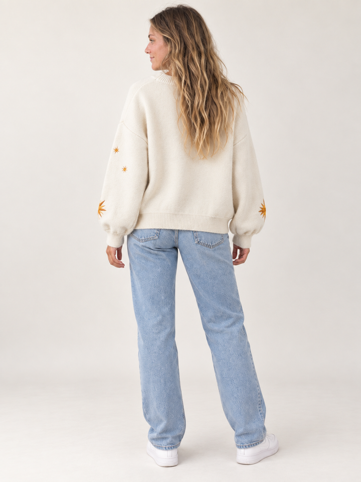 Model wearing oversized ivory embroidered sunburst and star cardigan, back view