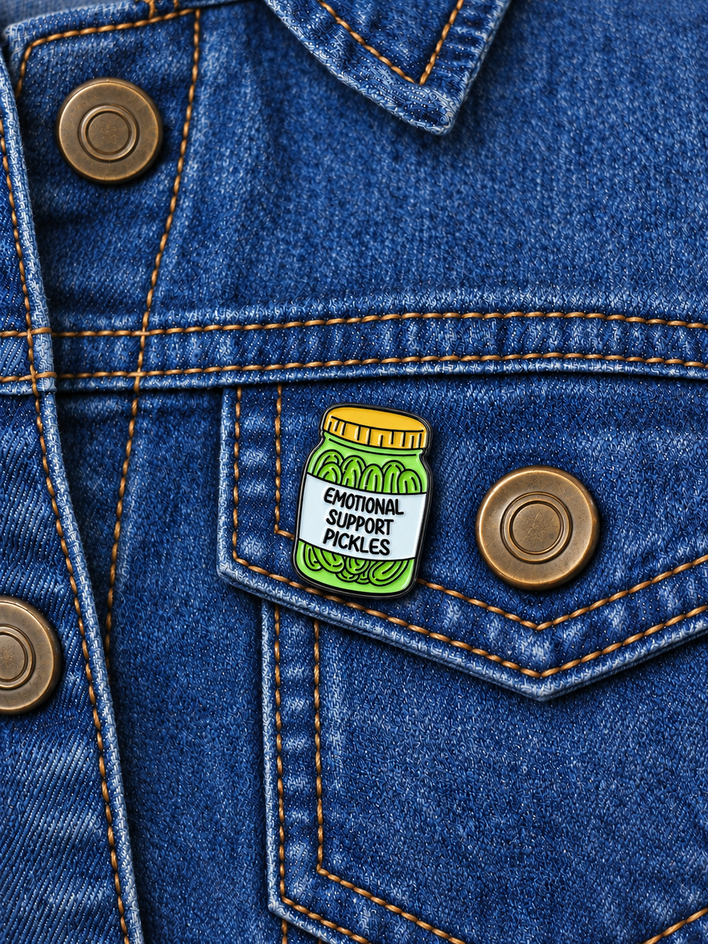 Emotional Support Pickles Pin displayed on a vintage blue denim jacket beside a metal button