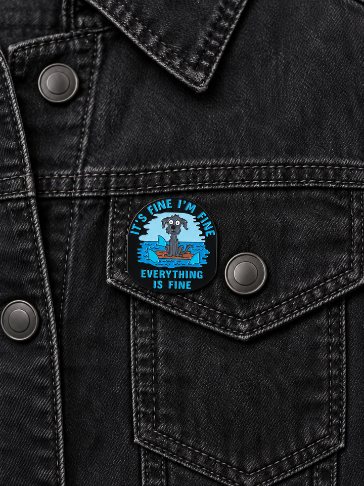 Everything Is Fine Dog Pin displayed on a black denim jacket beside a metal button