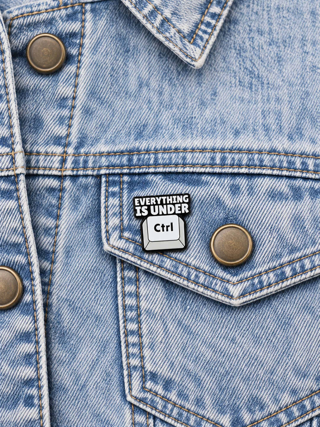 Everything Is Under Ctrl Pin displayed on acid-wash denim beside an antiqued brass button