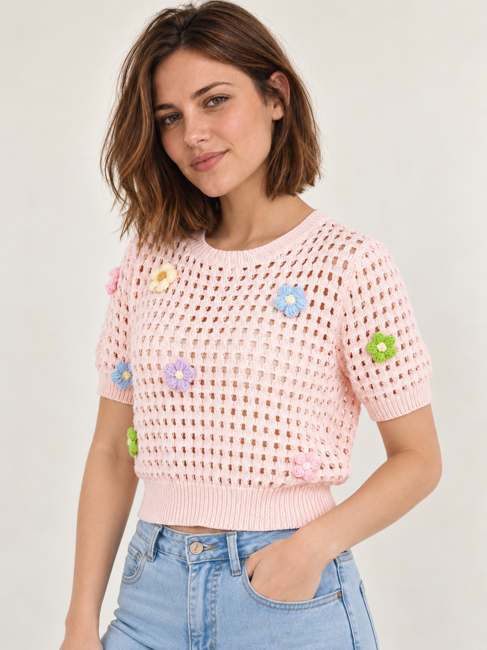 Model wearing Flower Open Knit Short Sleeve Top Pink over an ivory scoop-neck tank, angled view