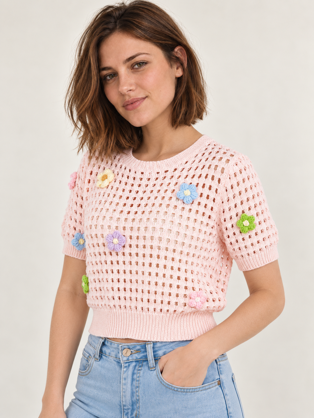 Model wearing Flower Open Knit Short Sleeve Top Pink over an ivory scoop-neck tank, angled view