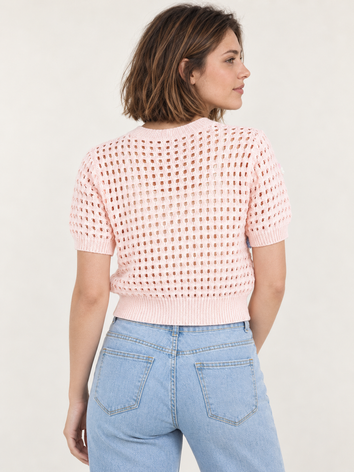 Model wearing Flower Open Knit Short Sleeve Top Pink over an ivory scoop-neck tank, back view