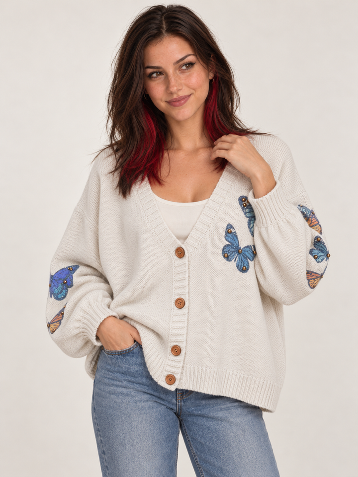 Angled view of oversized ivory butterfly cardigan styled with scoop-neck shirt and jeans
