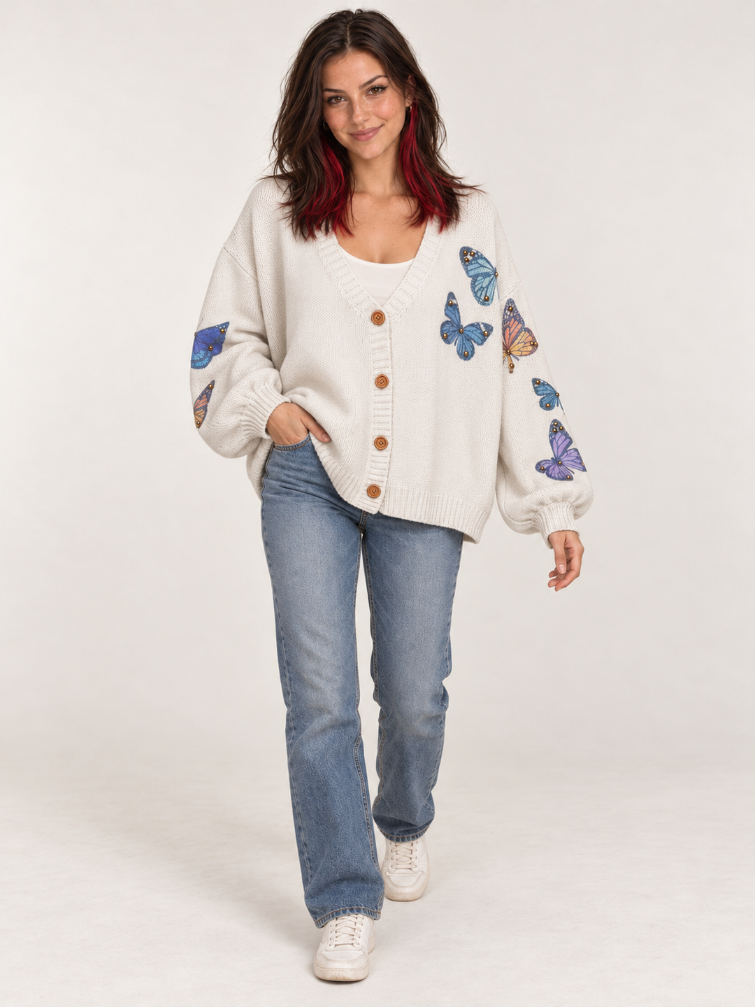 Full-body view of model wearing ivory butterfly cardigan with blue jeans and cream sneakers
