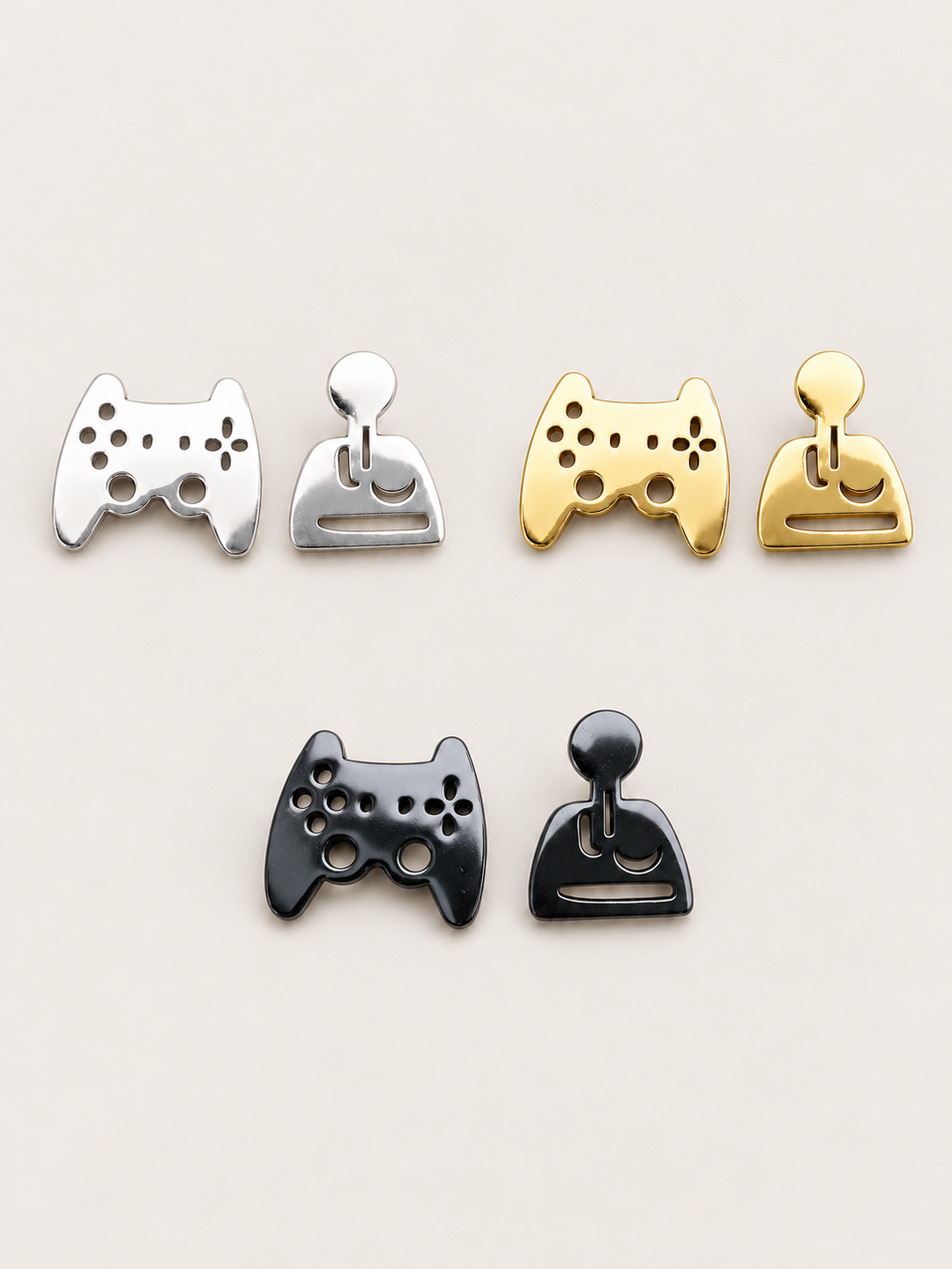 Game Controller and Joystick Earrings in silver, gold, and black on a warm neutral background